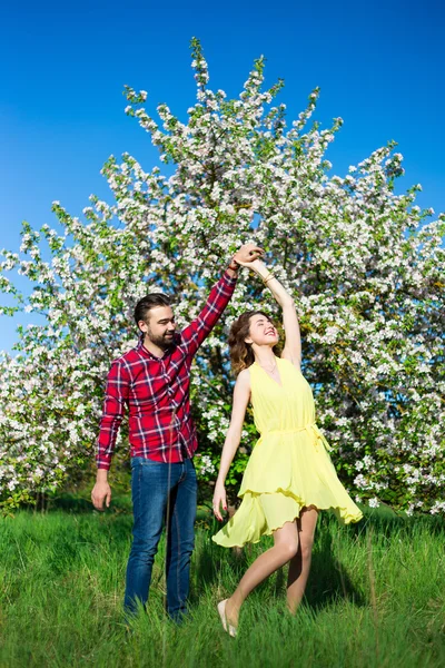 Young beautiful couple in love dancing in blooming garden — Stock Photo, Image