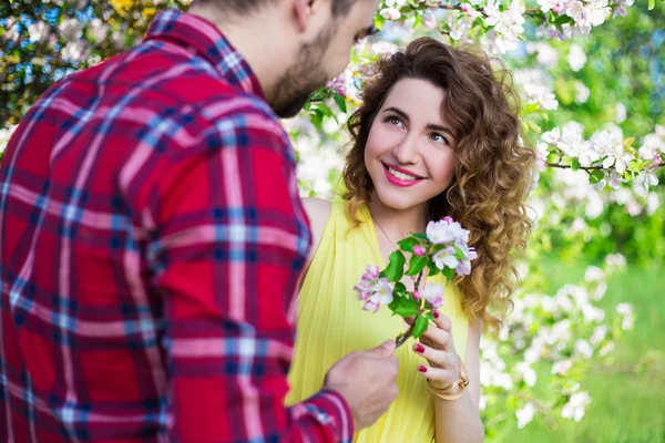 Junger Mann glücklich Freundin im Garten Blumen schenken — Stockfoto