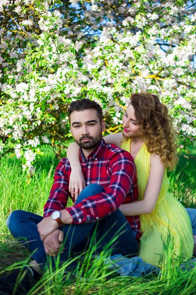 Молодая красивая пара в любви, сидя в цветущий сад — стоковое фото