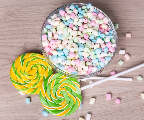 Mini marshmallows and lollipops on wooden table — Stock Photo, Image