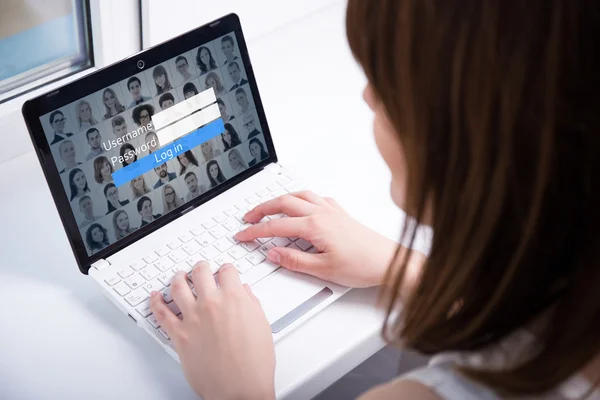 Back view of woman using laptop with login box on screen — Stock Photo, Image