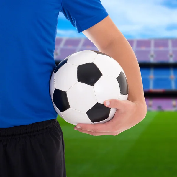 Fotbalový míč v ruce hráče na poli velkých stadionu — Stock fotografie