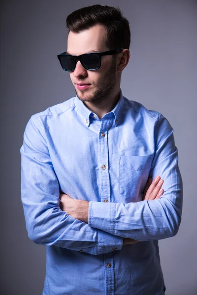 Schönen jungen Mann mit Sonnenbrille posiert in grau — Stockfoto