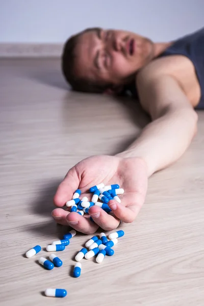 Overdose o suicidio - uomo con le pillole sdraiato sul pavimento — Foto Stock