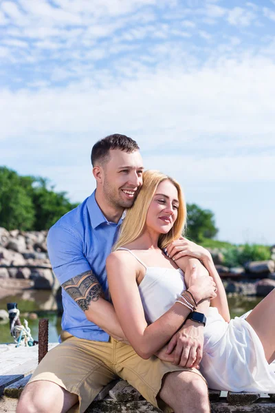 Lyckliga romantiska unga paret sitter på piren och njuta av havet — Stockfoto