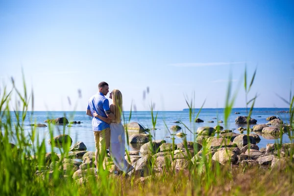 Arkadan görünüşü güzel çift aşık kayalık plaj — Stok fotoğraf