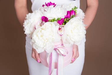 bej renkli arka plan üzerinde eller Şakayık çiçekleri kutusuyla