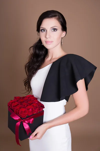 Portrait of beautiful woman holding box with red flowers — Stock Photo, Image