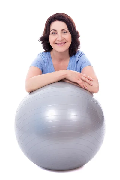 Happy sporty mature woman sitting with fitness ball isolated on — Stock Photo, Image