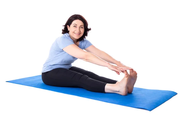 Mulher madura feliz fazendo alongamento exercícios na esteira isolat ioga — Fotografia de Stock