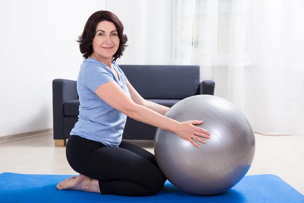 Delgado deportiva mujer madura haciendo ejercicios con la bola de la aptitud en el yo — Foto de Stock