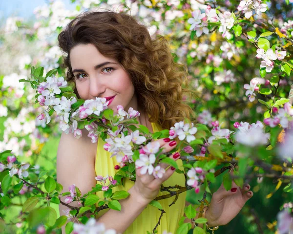 Portrait of young beautiful woman smelling apple tree branch in — Stock Photo, Image