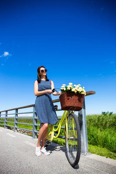 Frau im Kleid posiert und Vintage Fahrrad mit Weidenkorb in — Stockfoto