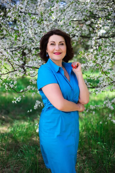 Portrait of happy middle aged woman in blooming garden — Stock Photo, Image