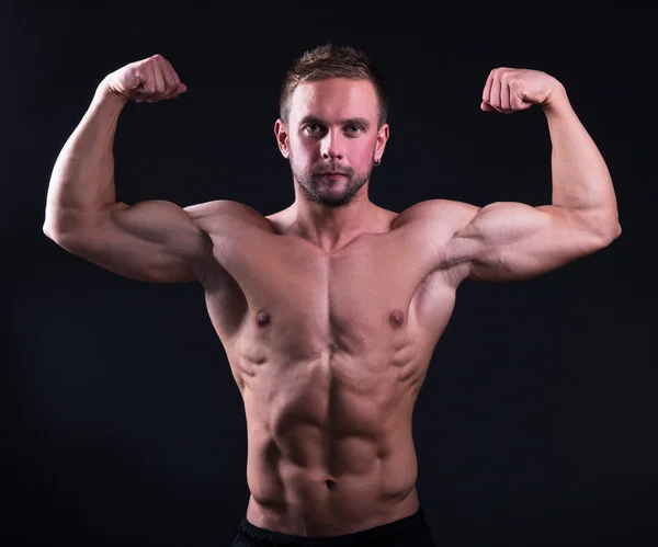 Porträtt av stilig muskulös man visar sina muskler över grå — Stockfoto