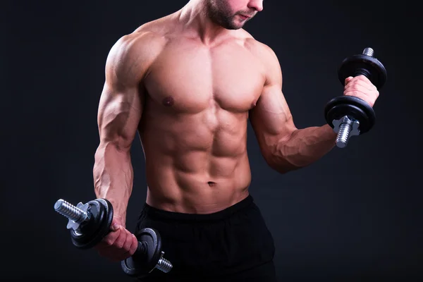 Muskulös kropp av ung man poserar med hantlar över grå — Stockfoto