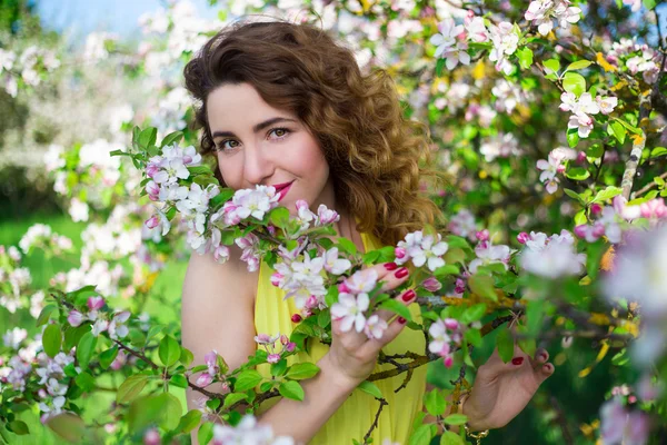 Portrait of young beautiful woman smelling apple tree branch in — Stock Photo, Image