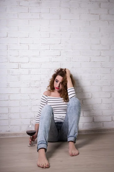 Smutna kobieta siedzi na podłodze, płacz i picie wina — Zdjęcie stockowe
