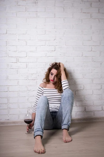 Sad woman sitting on the floor, crying and drinking wine — Stok Foto