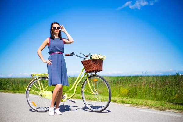Glückliche Frau posiert mit Retro-Fahrrad auf der Straße über den blauen Himmel — Stockfoto