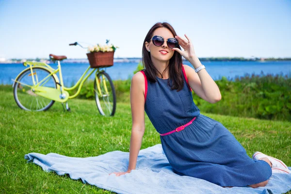 Žena v sluneční brýle sedí na pobřeží moře s vintage bicycl — Stock fotografie