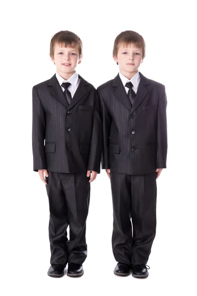 Pequenos irmãos gêmeos em ternos de negócio isolados no branco — Fotografia de Stock