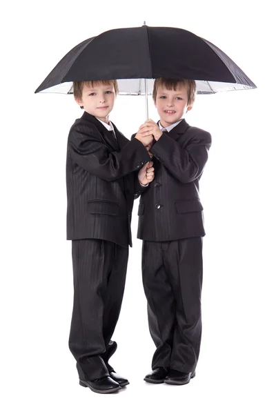 Two cute little boys twins in business suits with umbrella isola — Stock Photo, Image