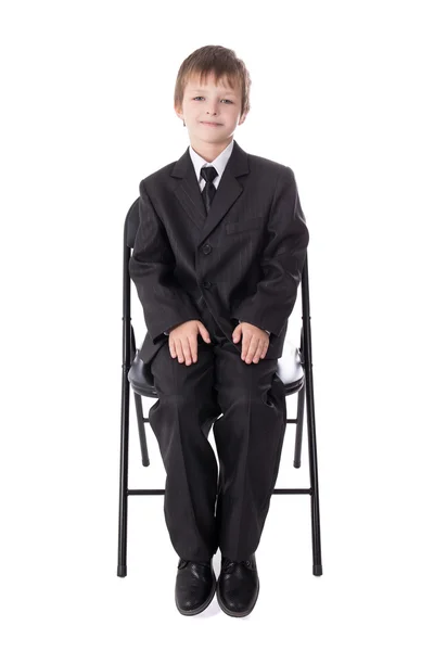Маленький мальчик в деловом костюме, сидя на офисный стул, изолированные на — стоковое фото