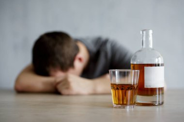 Alkolizm ve depresyon kavramı. Bardak, viski şişesi ve masada yatan sarhoş adama yakın.