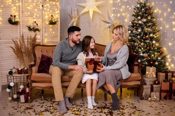 happy young family sharing gifts in living room with decorated Christmas tree
