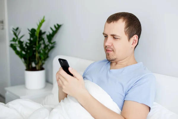 Retrato Jovem Homem Bonito Sentado Cama Usando Smartphone — Fotografia de Stock