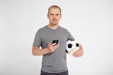 spor, online bahis, başarı, kazanç ve para konsepti - akıllı telefon kullanan genç adamın portresi ve avro parası ile futbol topunu fotokopi alanı olan gri arkaplan üzerinde tutmak