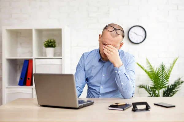 business, work, financial crisis and stress concept - businessman sitting in office and covering face with his hand