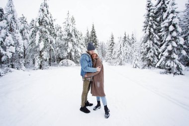 Genç ve güzel bir çift kış ormanında kucaklaşıyorlar.