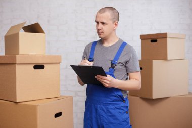 Posta teslimatı ve taşınma günü konsepti - yükleyici ya da kurye panoda bir şeyi kontrol ediyor