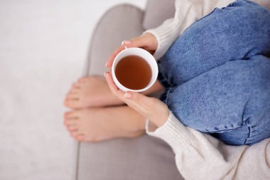 Kadın bacakları ve elleri bir fincan çayla kapatın.