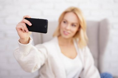 Genç ve güzel bir kadın akıllı telefonuyla selfie çekiyor. Telefona odaklan.