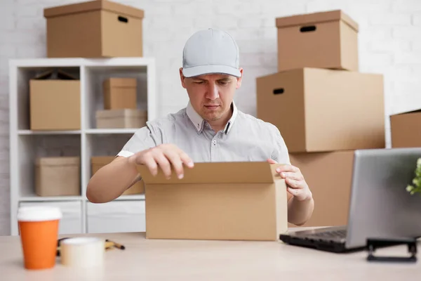 work and business concept - postman opening or packing parcel in post office