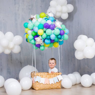 Çocukluk, hayaller ve yaratıcılık konsepti. Stüdyoda renkli hava balonu sepetinde oturan küçük kız.