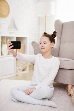 teknoloji, sosyal medya ve internet konsepti - evde akıllı telefonla fotoğraf çeken küçük kız portresi