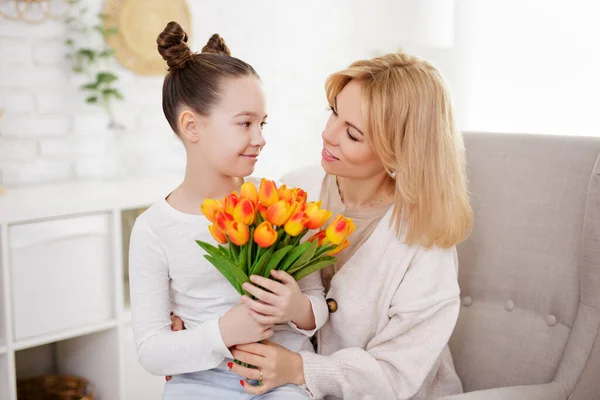 家族と母の日のコンセプト 明るいリビングルームで母親に花を贈るかわいい女の子 — ストック写真
