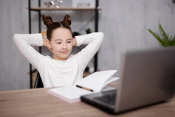 school, homework and distance education concept - school girl doing homework with laptop, studying online or watching movie at home