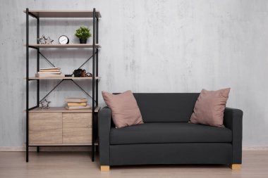 Kitapları ve kanepesi olan raf - beton duvar arkaplanının üzerine alanı kopyala