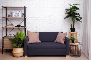 Kanepesi, masası, rafı ve bitkileri tuğla duvarın üzerinde.