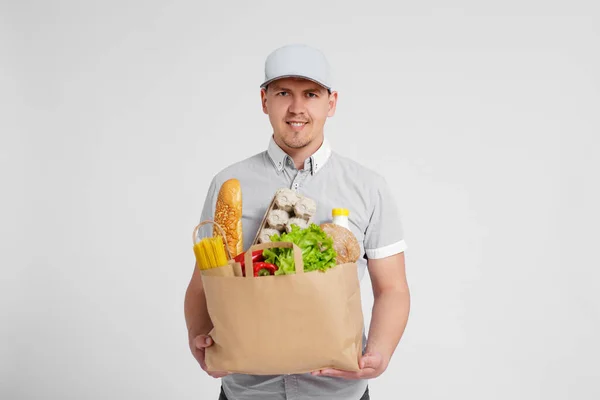 Repartidor Uniforme Sosteniendo Bolsa Papel Llena Productos Sobre Fondo Blanco —  Fotos de Stock