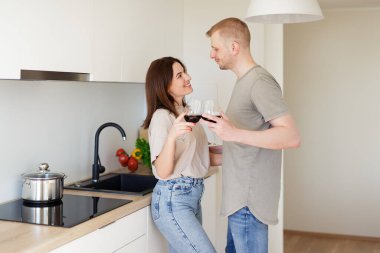 Aşk, flört ve romantizm - parlak mutfakta kırmızı şarap içen genç bir çiftin portresi