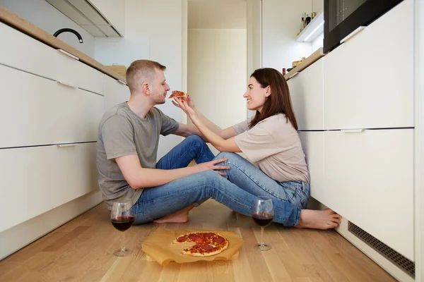 portrait of happy couple in love eating pizza and drinking wine in the kitchen