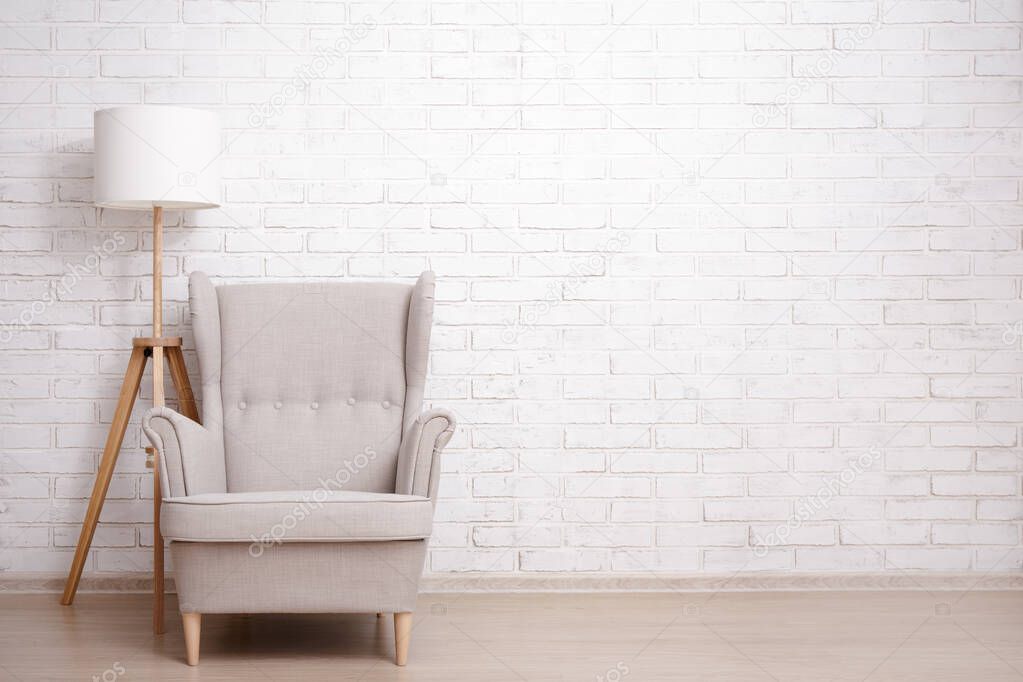 Modern armchair and lamp with copy space over brick wall background
