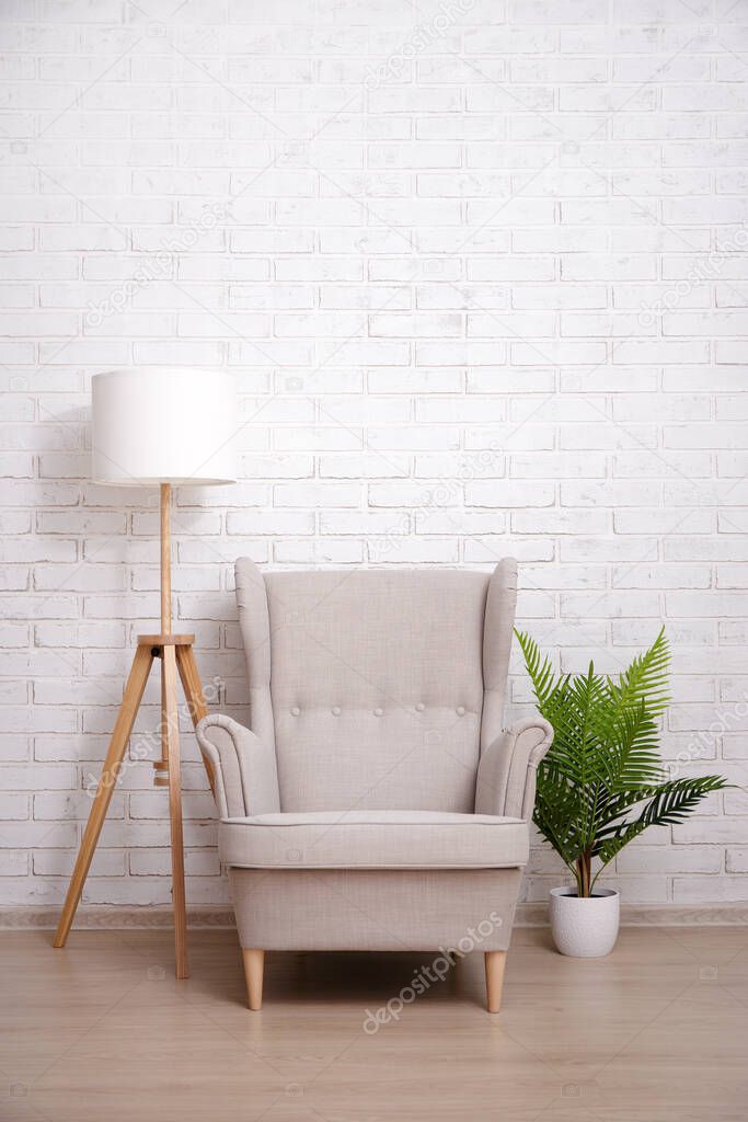 Armchair, lamp and plant with copy space over brick wall background
