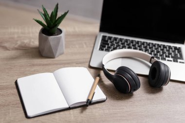 İş ve eğitim konsepti - dizüstü bilgisayarı, kulaklığı olan işyeri, kopya alanı ve kalemi olan boş not defteri